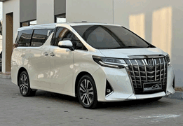 Toyota Alphard warna bronze/gold metalik generasi terbaru difoto dari sudut depan samping, menampilkan desain grille depan besar dan mewah dengan pola mesh unik, headlamp LED tajam menyatu dengan garis body, sliding door elektrik, serta interior kabin VIP yang identik dengan kenyamanan kelas atas. Sebagai armada paling premium sewa mobil di Medan, Alphard menjadi pilihan utama untuk jemputan tamu VVIP, wedding car mewah, rombongan pejabat/eksekutif perusahaan, hingga perjalanan bisnis kelas atas yang mengutamakan privasi dan kenyamanan maksimal.
